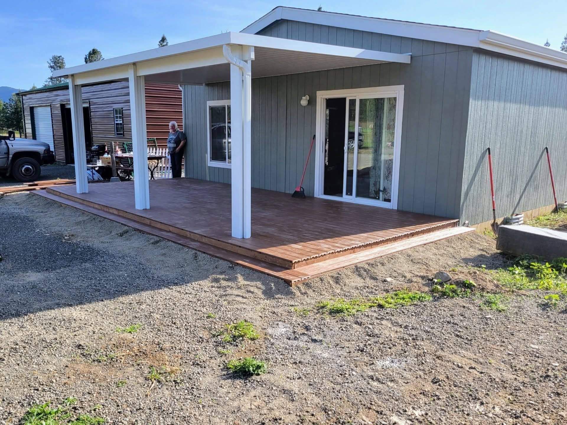 A custom-framed covered porch with composite decking built onto a rural home