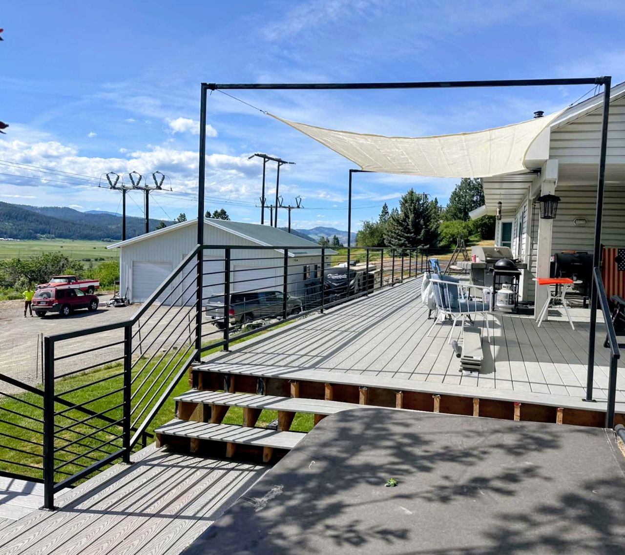 A custom 60-foot elevated residential deck showcasing dual staircases, a built-in safety gate, shop-welded steel railings, and heavy-duty structural sunshade mounts.