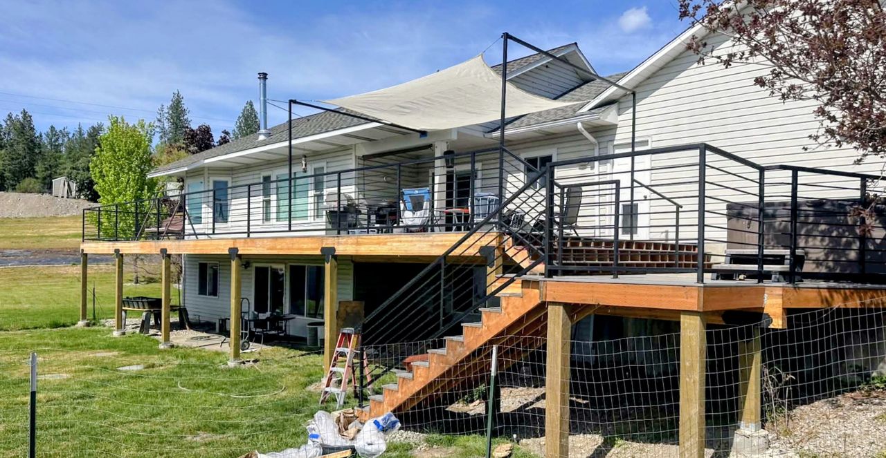 A custom 60-foot elevated deck spanning the rear of a home, with dual stair runs and fabricated steel handrails.