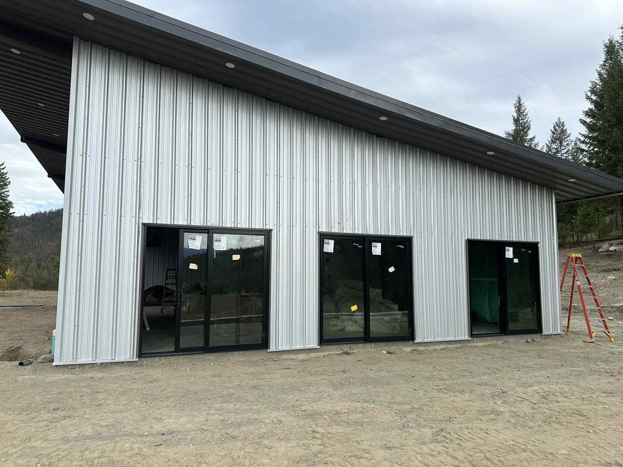 Exterior view of a custom 75-by-50-foot commercial steel structure building outfitted with Roll-A-Shield security doors, handcrafted wooden sliding barn doors, and Wayne Dalton roll-up service doors.