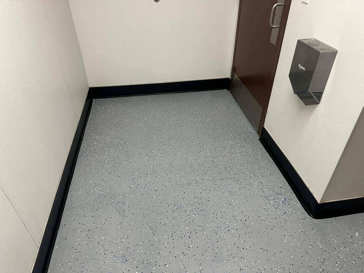 A newly installed, seamless epoxy floor coating featuring a matching, continuous curved cove base along the wall foundation.