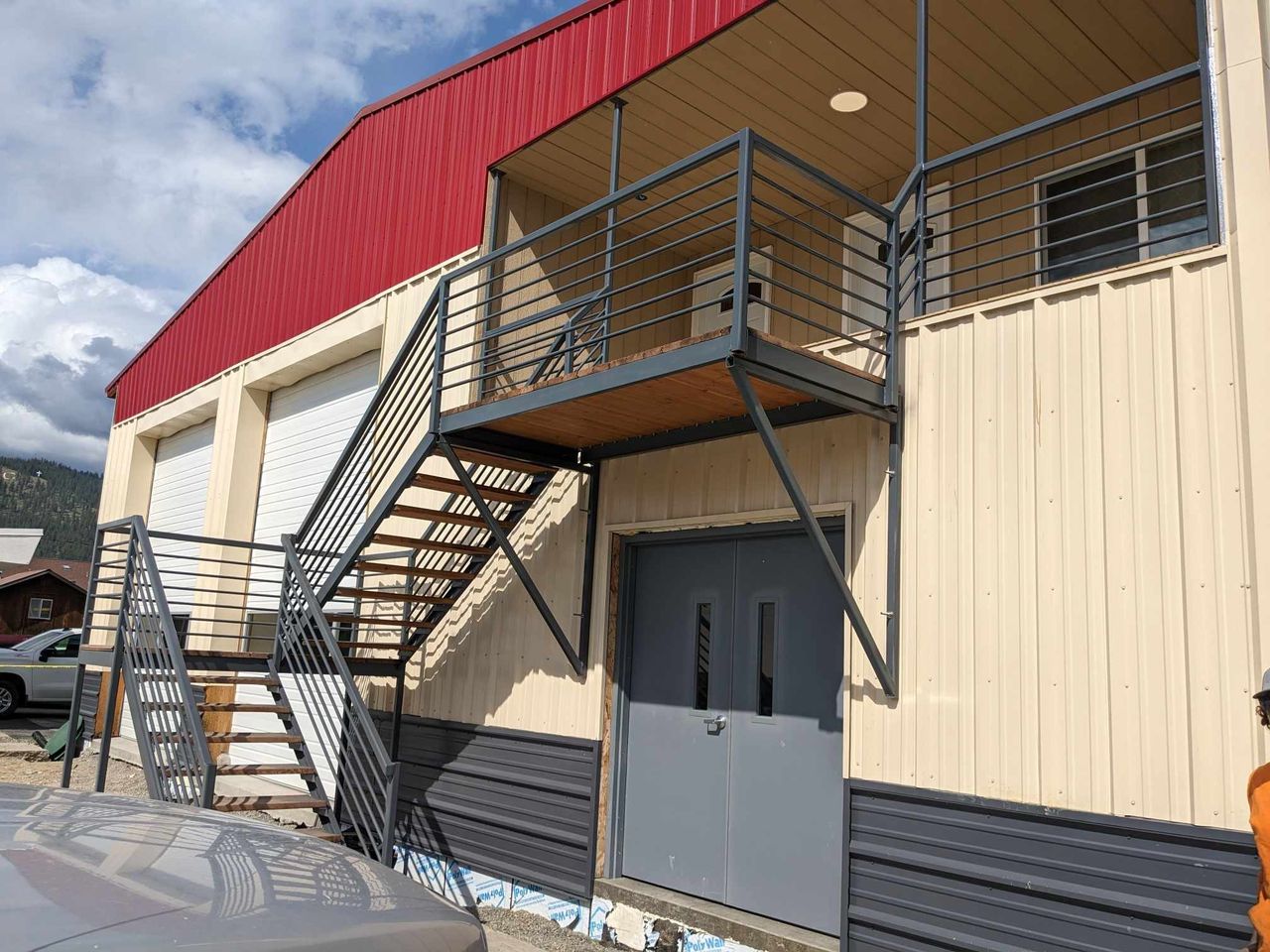 Fabricated steel exterior staircase and balcony landing welded onto a commercial metal building.