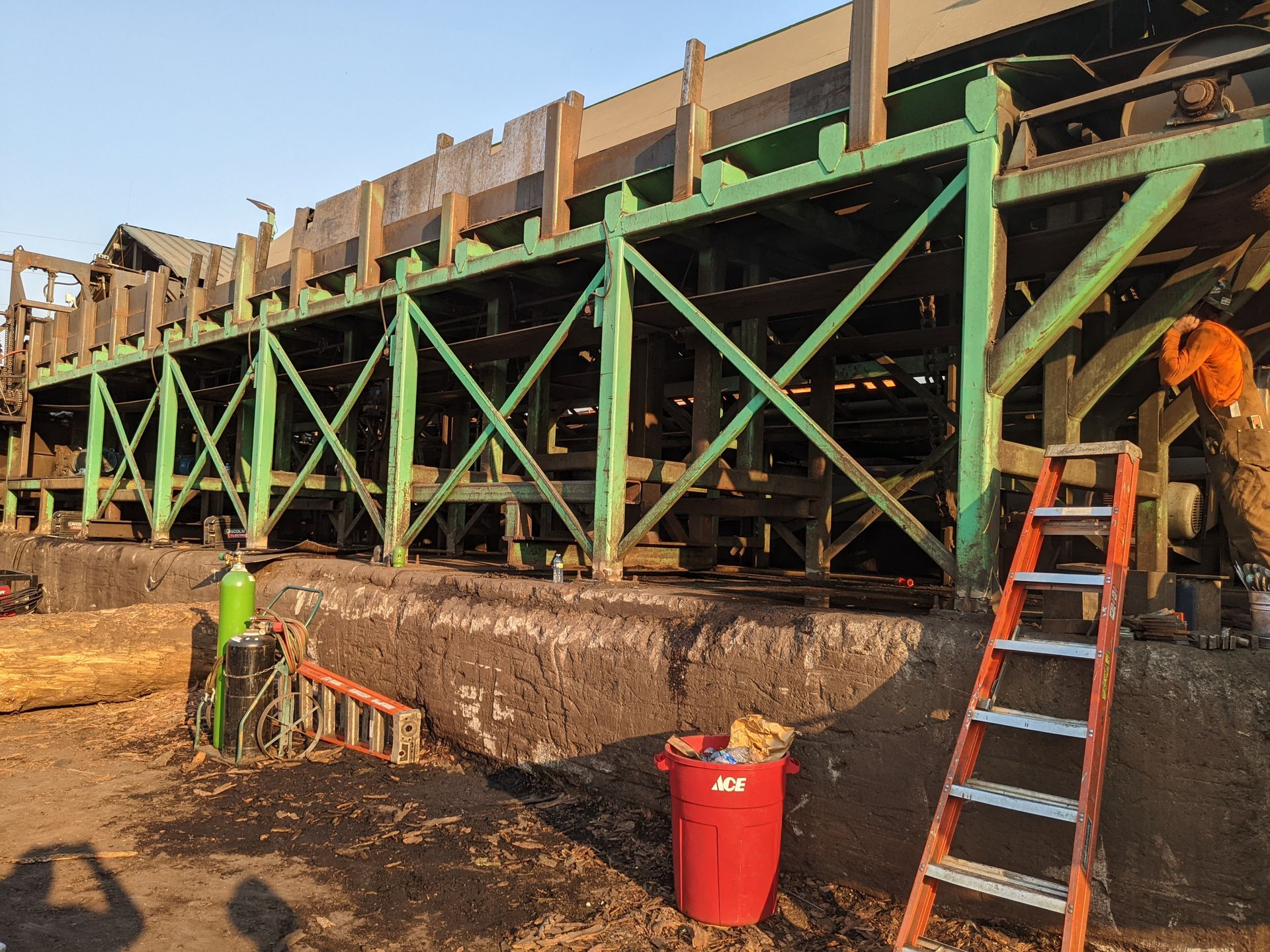 Welder repairing the structural steel framework of a sawmill conveyor deck in Colville, WA